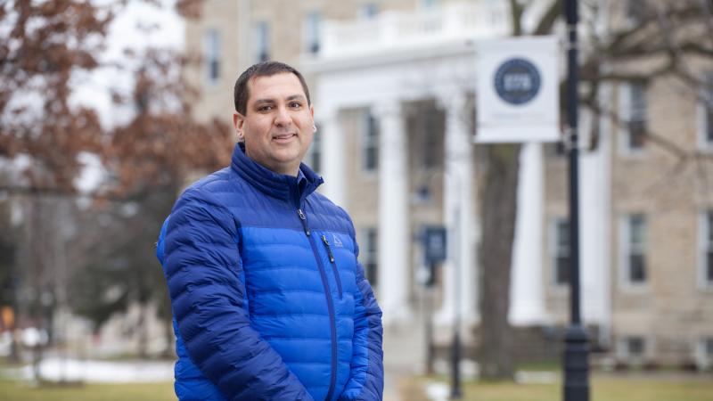 Brian Piasecki stands for a photo on the sidewalk leading to Main Hall.