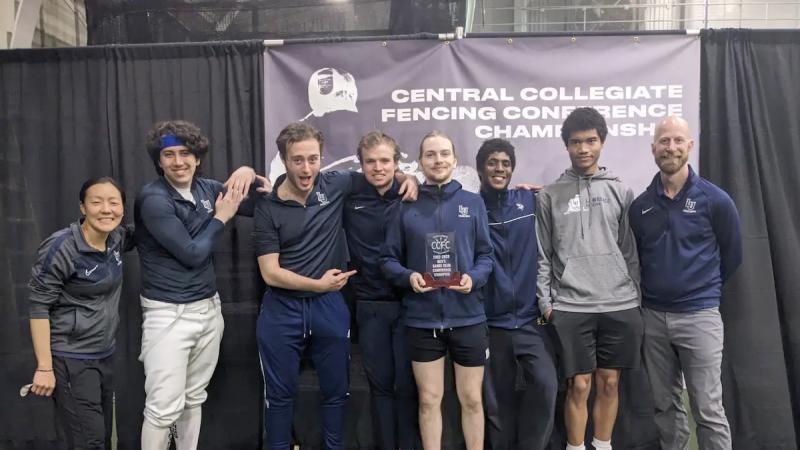 Saber athletes and coach Eric Momberg show the championship trophy.