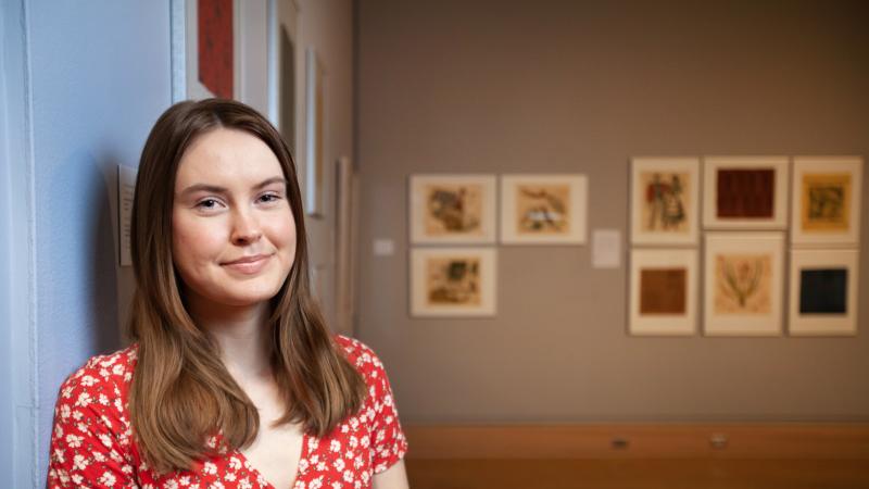 Sarah Matthews poses for a photo amid her art exhibit in Wriston Art Galleries.