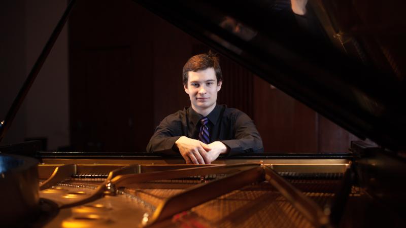 Jonathan Bass poses for a portrait with a piano in the Music-Drama Center.