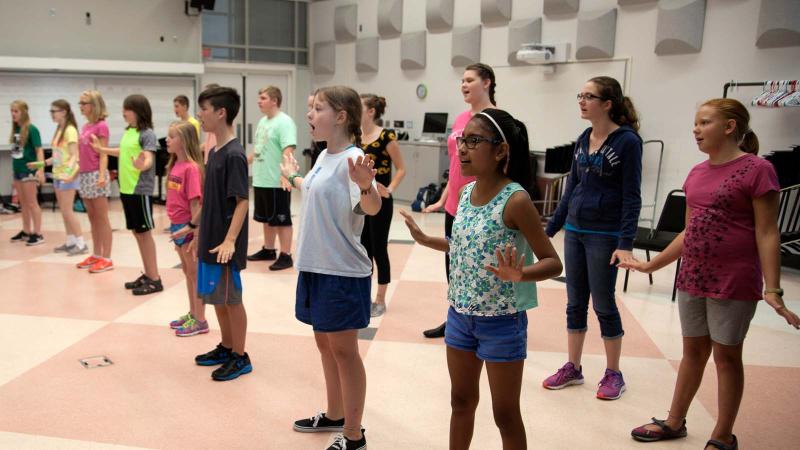 Elementary-aged students learning choreography for a musical