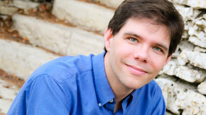 Portrait of Brooke Joyce as he sits on steps made of stone.