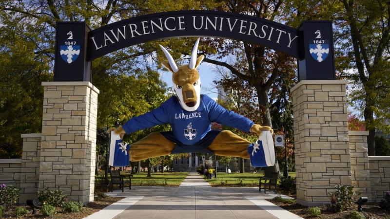 Mascot Blu in front of campus arch