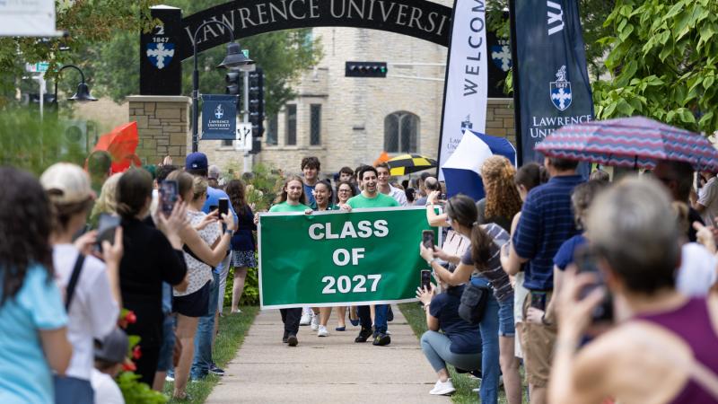 Members of the Class of 2027 hold their green class banner as they walk beneath the Lawrence Arch on their way to the President's Welcome.