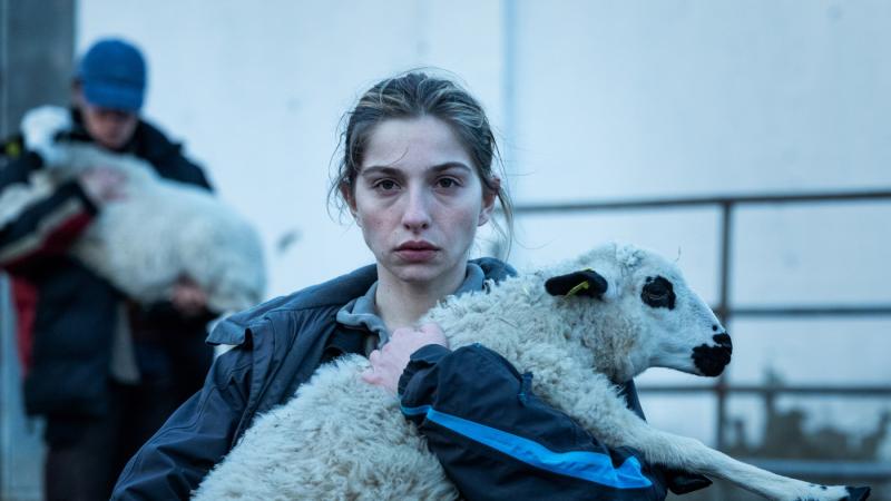 A still from the film As Bestas shows a woman holding a sheep.