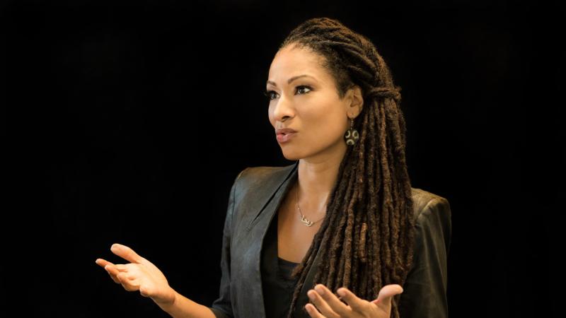 Ruha Benjamin gestures as she speaks to an audience.