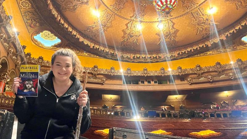 Schuyler Thornton '14 holds a playbill for "Les Miserables" and her flute as she poses for a photo on stage. 
