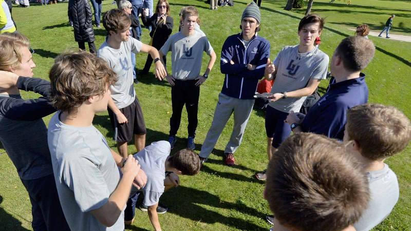 Viking Men's Cross Country Team huddled around coach