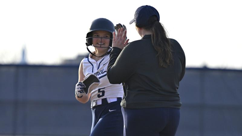 Taylor Hughes high fives a coach during a softball game.
