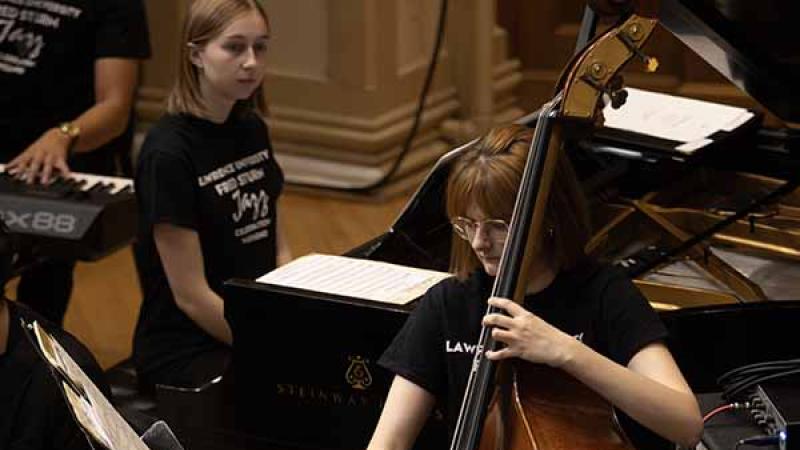 Bass player and piano player in black Jazz Weekend t-shirts perform on the chapel stage