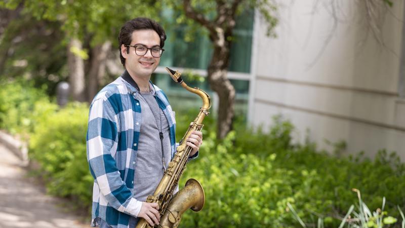 Eli Elder poses for a photo outdoors with his saxophone.