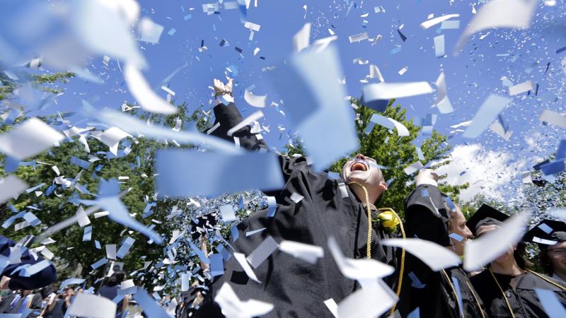 Confetti and graduation caps fly as graduates celebrate at the close of Commencement.