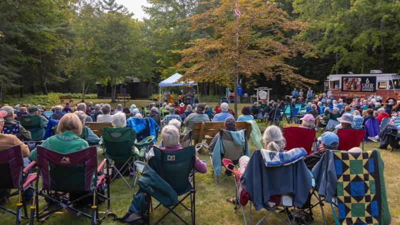 a crowd gathers in front a musicians performing under a tent