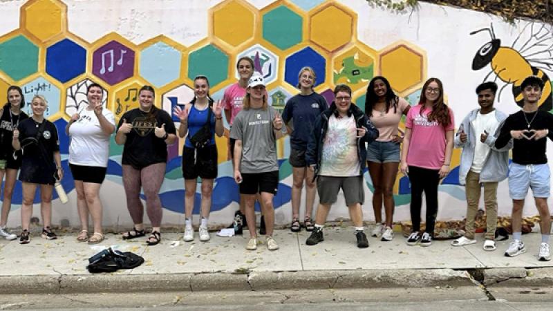 Students in front of Drew Street Wall Mural they painted for Pre-Orientation Experience