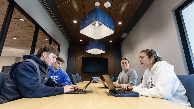 Business & Entrepreneurship students working on business pitch with advisors in B&E Center Board Room