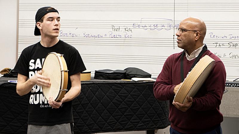 Student and faculty play hand held drum in class