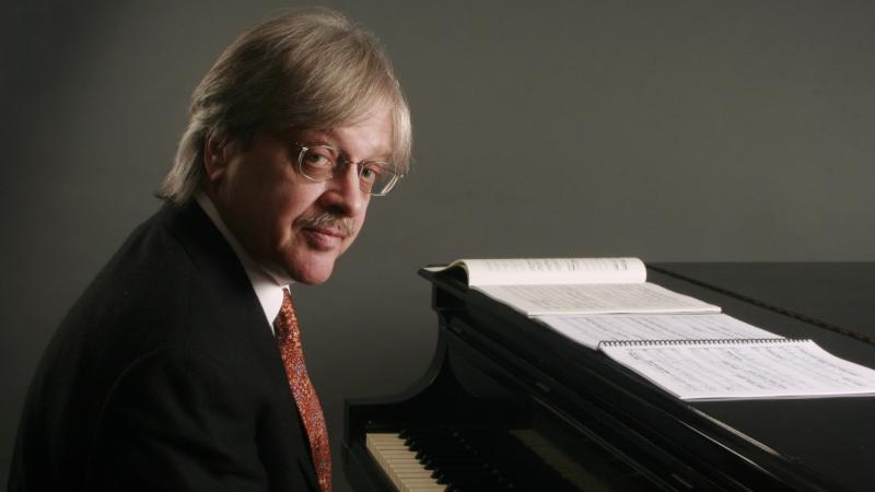 Fred Lerdahl poses for a photo at a piano.