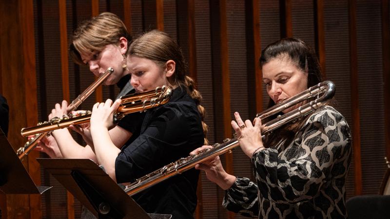 Flutists playing alto and bass flutes.