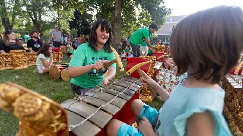 A woman teaching a child how to play gamelan.
