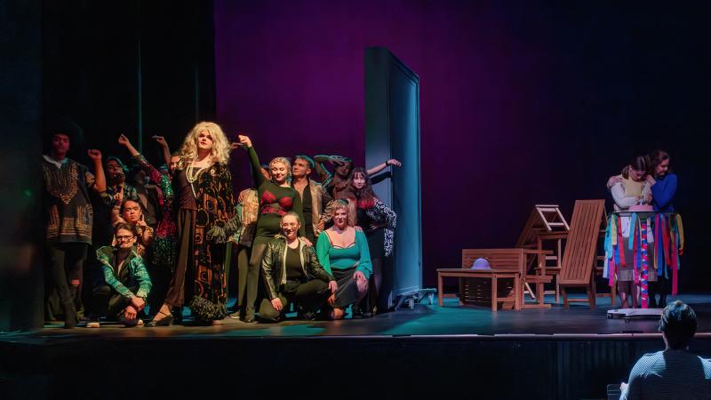 An ensemble of costumed performers on a stage divided into three sections.
