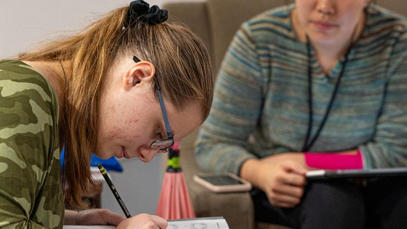 A student doing homework under the guidance of a student tutor.