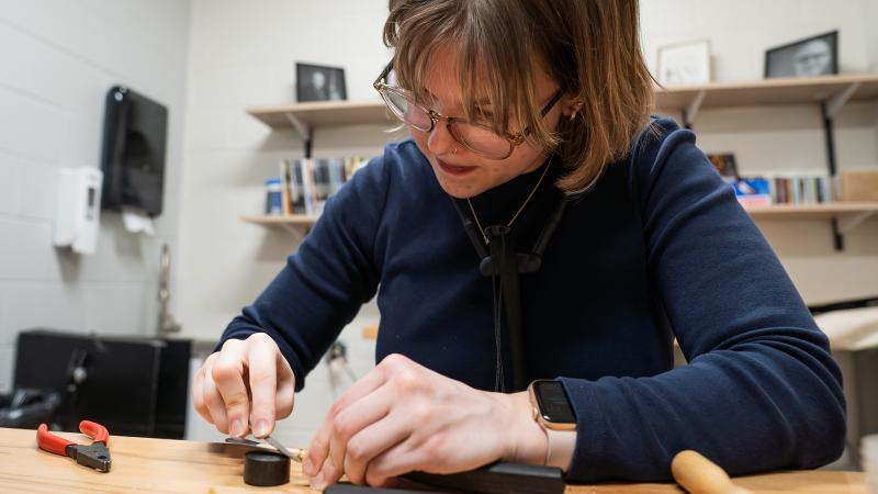 A student using tools to work on a bassoon reed.