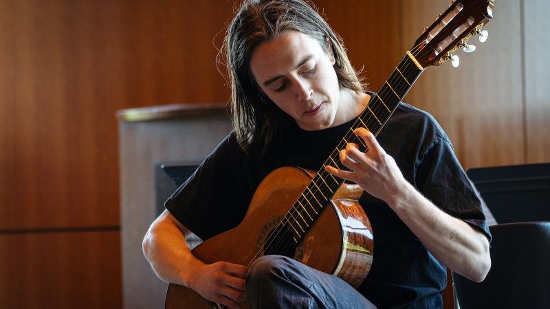 A student focused on playing acoustic guitar.