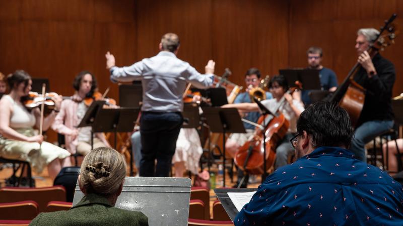 Composers observing an ensemble rehearsing their work.