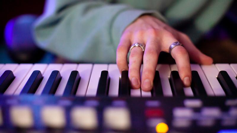 A close-up shot of a hand playing an electric keyboard.