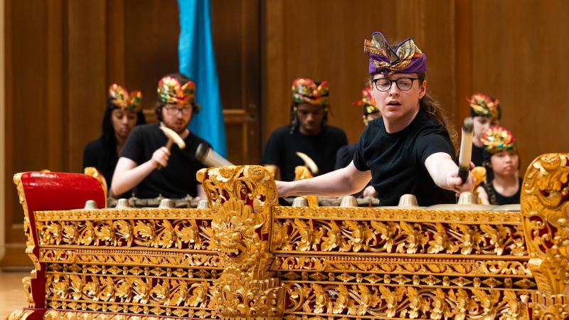 An ensemble of costumed musicians playing gold and red metallophone instruments.