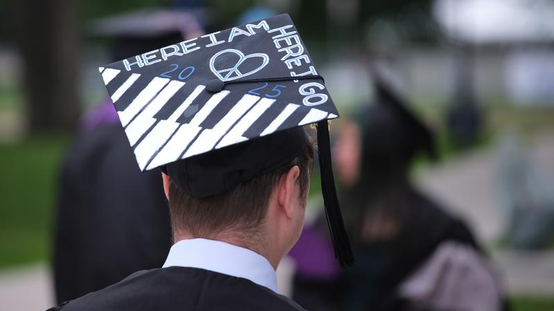 A graduation cap decorated with a piano keyboard and the phrase, "Here I Am, Here I Go".