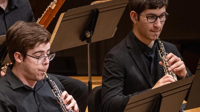 Two students playing oboes in concert.