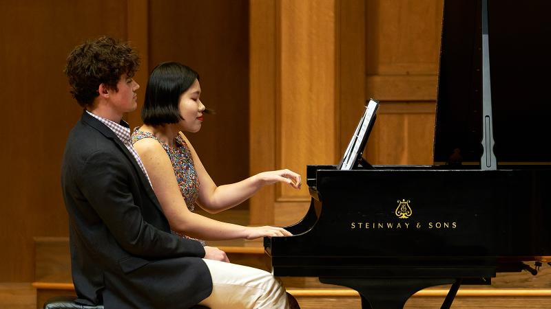 Two musicians playing piano 4-hand in performance.