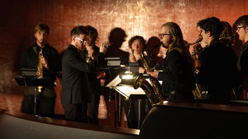 A conductor leading an ensemble of saxophonists.