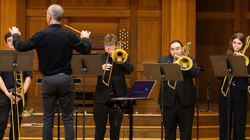 An ensemble of musicians playing trombones.