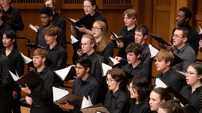Rows of choral singers on tiered risers in concert.