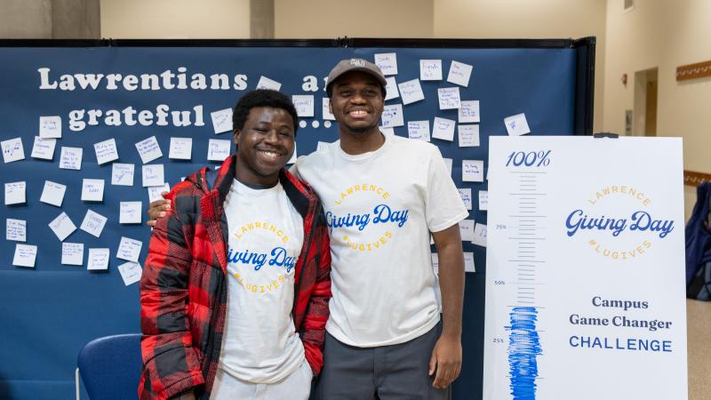 Two students stand by the Gratitude Board on Giving Day