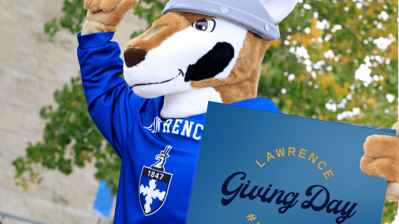 Blu cheers on the crowd while holding a Giving Day sign