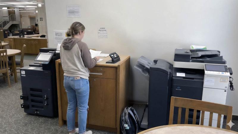 Student at counter near copier in library