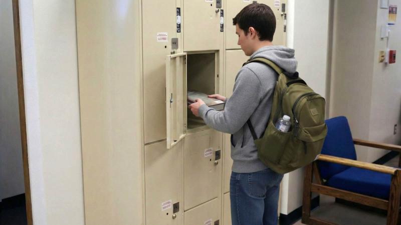 Student placing book in library locker