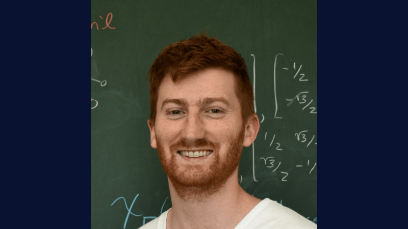 Headshot of Alexander Heaton in front of a chalkboard