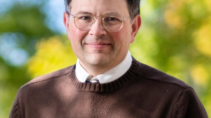 A person wearing a brown sweater and glasses