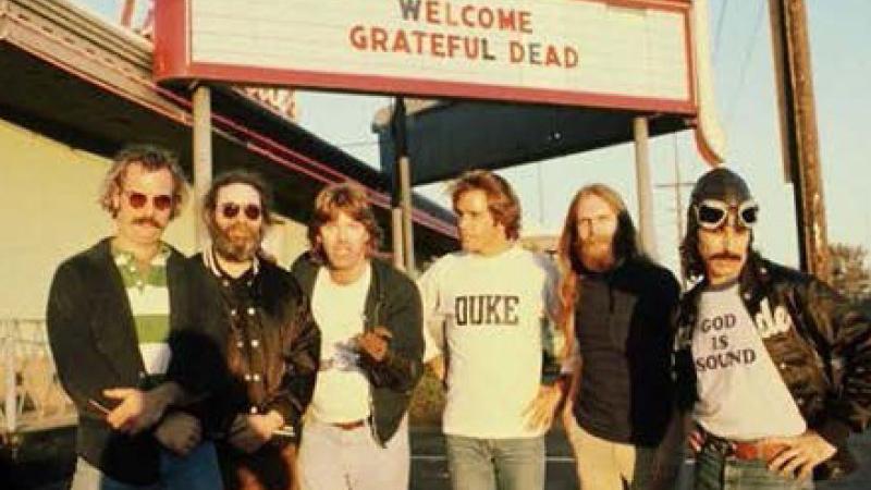 Band members standing in front of a marquee that reads Welcome Grateful Dead 