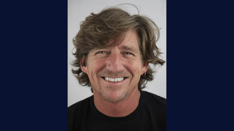 person wearing a black shirt, smiling, and with medium length hair 