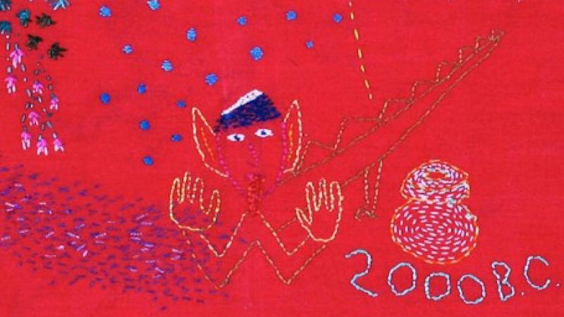 decorative stitching depicting a figure and "2000 BC" on a red cloth