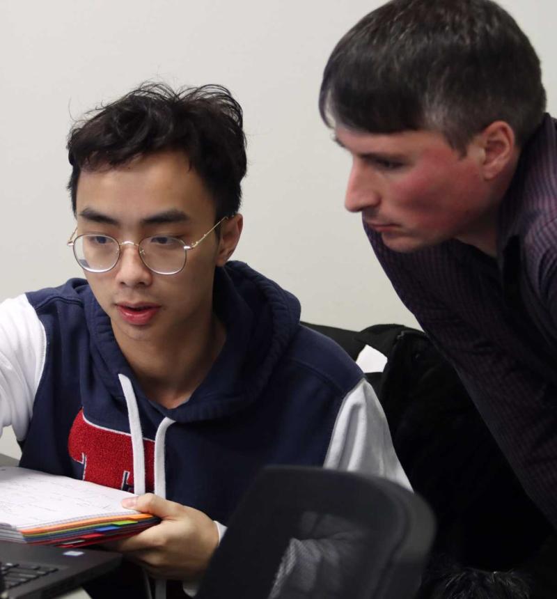 computer science professor helping student on laptop during class