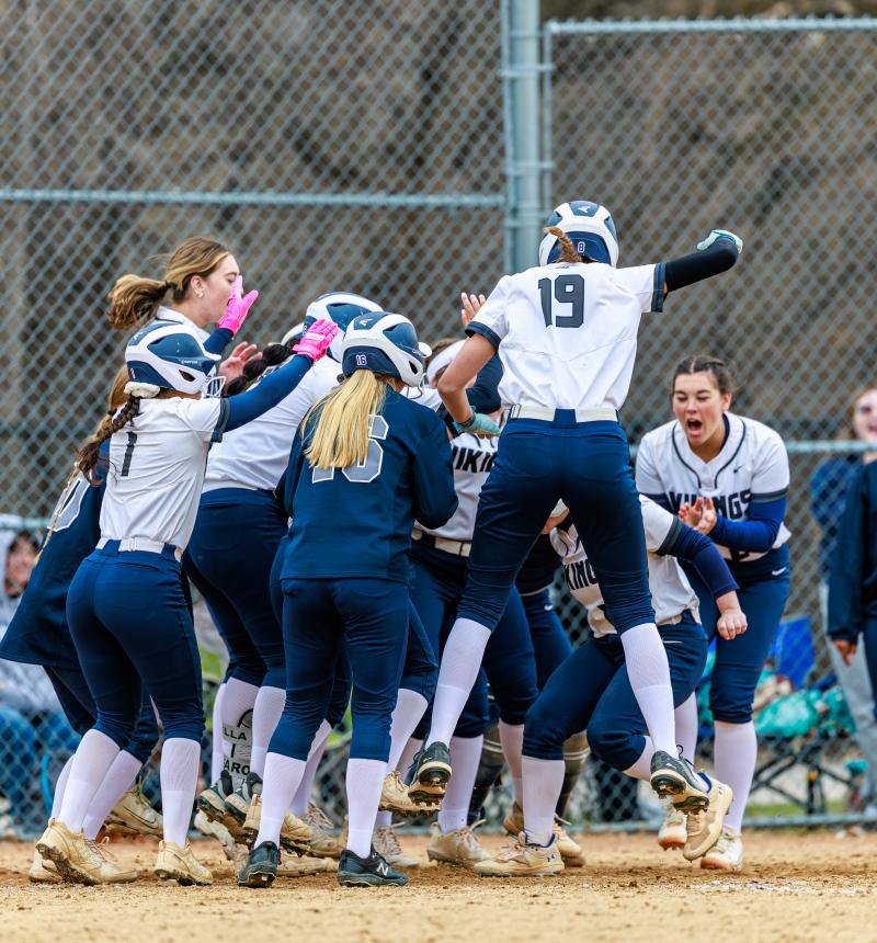 Softball team celebrating home run hit.