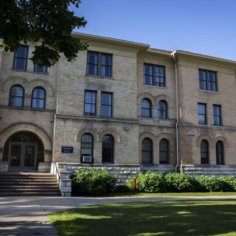 three-story brownstone building with a concrete path leading up to its short stone steps