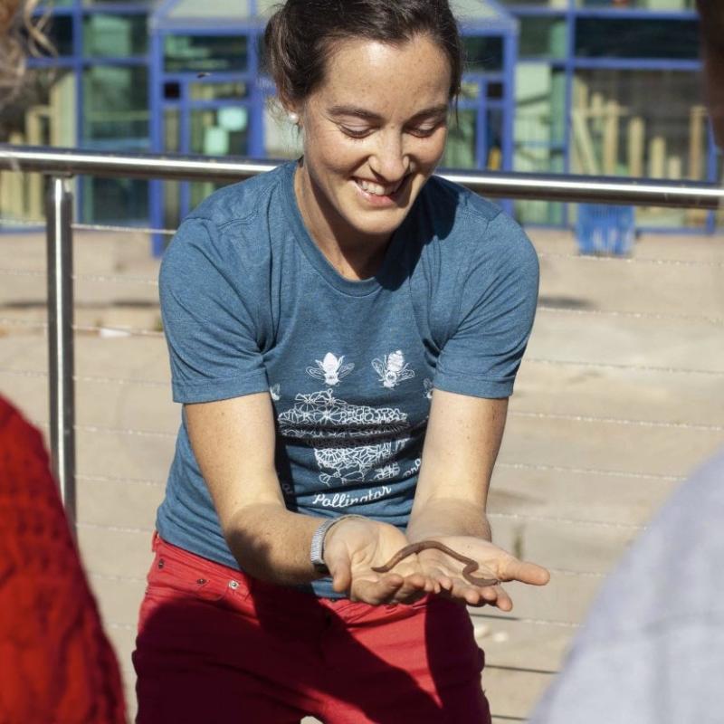 Dr. Ribbons, in red jeans and an Appleton Polliantor Project tshirt is holding up a worm to show students who lives right under our feet.