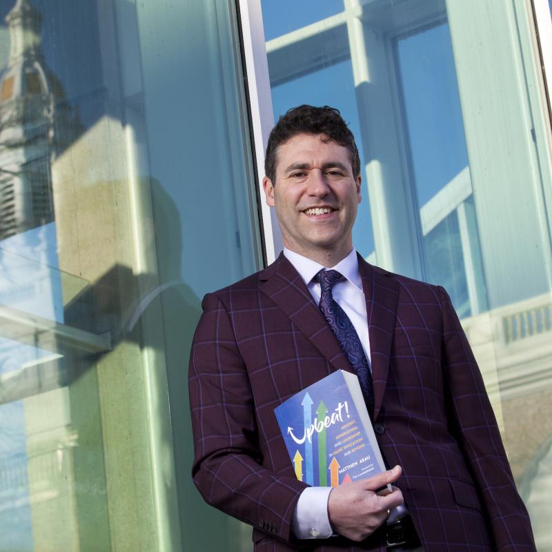 Dr. Matthew Arau outside the Conservatory with his book, "Upbeat!"